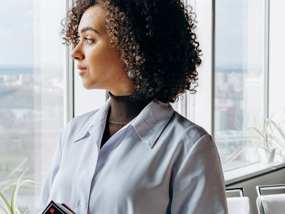 A woman standing at a window, looking out, deep in thought